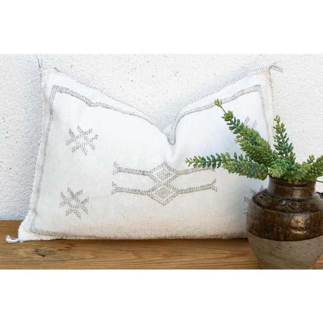 Two small star motifs sit above a stacked diamond medallion on this handcrafted Moroccan cactus silk lumbar pillow, hand-...