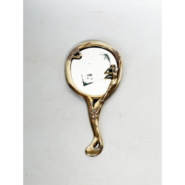 An elegant 20th-century French hand mirror, crafted from gilt metal in an Art Deco style with naturalistic influences. The...