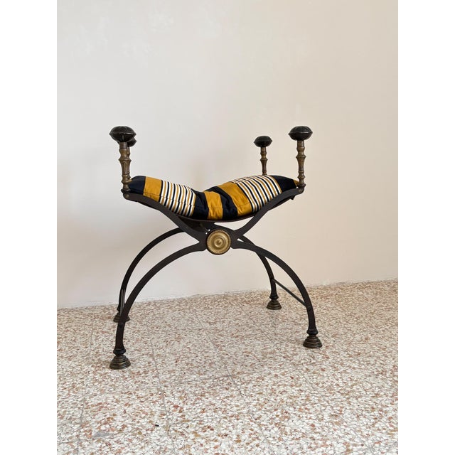 A stunning chair with a sculptural design, featuring a refined wrought iron frame, turned ends, brass details, and a...