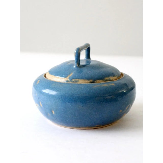 This vintage handmade studio pottery bowl features a beautiful blue glaze with a rustic finish. The lid with a handle adds...