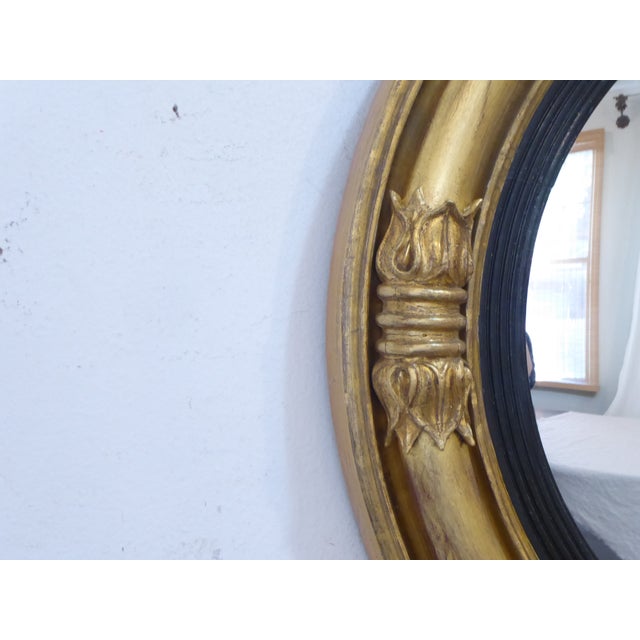 This 19th Century convex giltwood mirror has a rubbed gold patina.