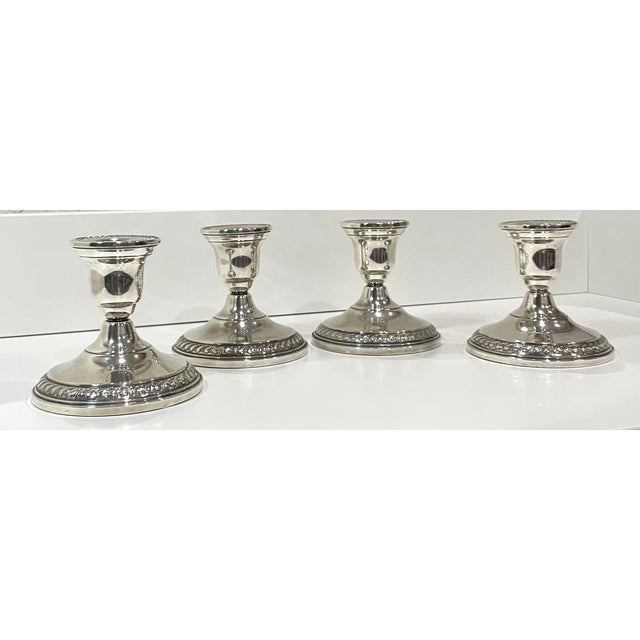 A set of four vintage Columbia sterling silver weighted candlestick holders with a rope design along the edge of the top...