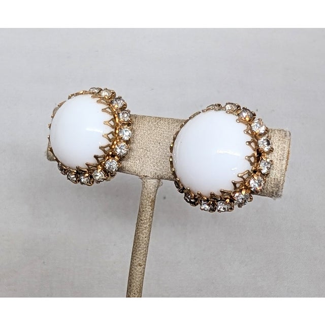 1960s round goldtone prong set white cabochon rhinestone center with small round clear rhinestone surround clip earrings....