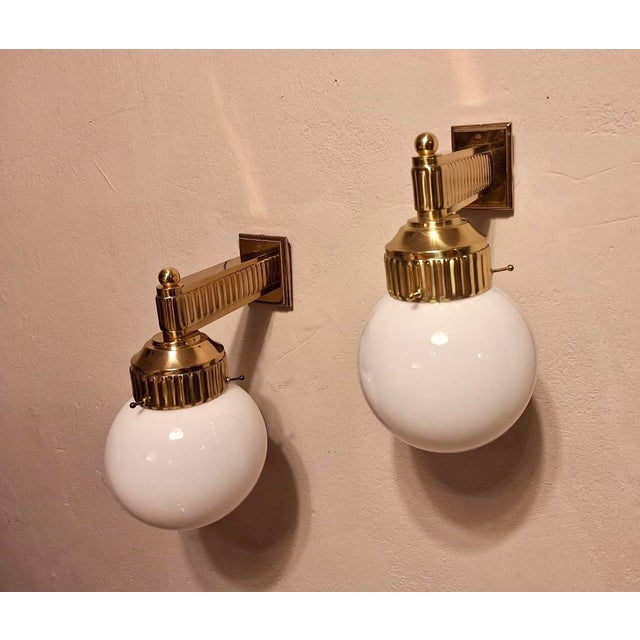 Pair of 'Astoria' wall lights in brass with opal glass globes. The original design was by Josef Hoffmann for the Grand...