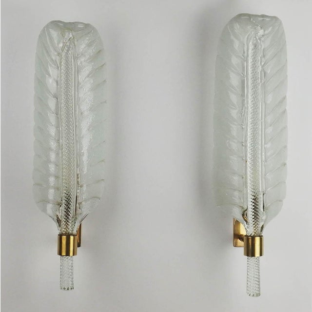 Pair of wall lights in thick, transparent glass in the shape of palm fronds mounted on brass supports. The design of these...