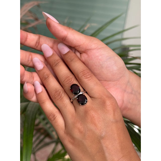 Handcrafted in 925 Sterling Silver, this ring highlights the beauty of garnet with two oval-cut stones weighing 8.47...