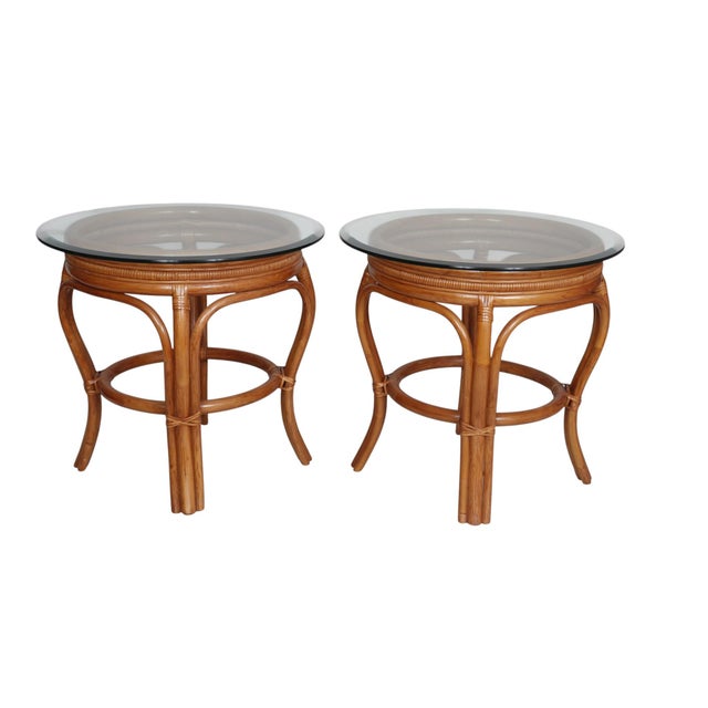 A pair of bamboo, rattan and glass side tables. Curvaceous bombé shaped bamboo frames are secured with rattan wrapped...