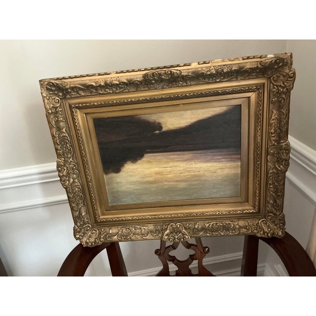 Atmospheric Tonalist landscape painting depicting a sweeping, muted countryside beneath a dramatic darkened sky. Rendered...