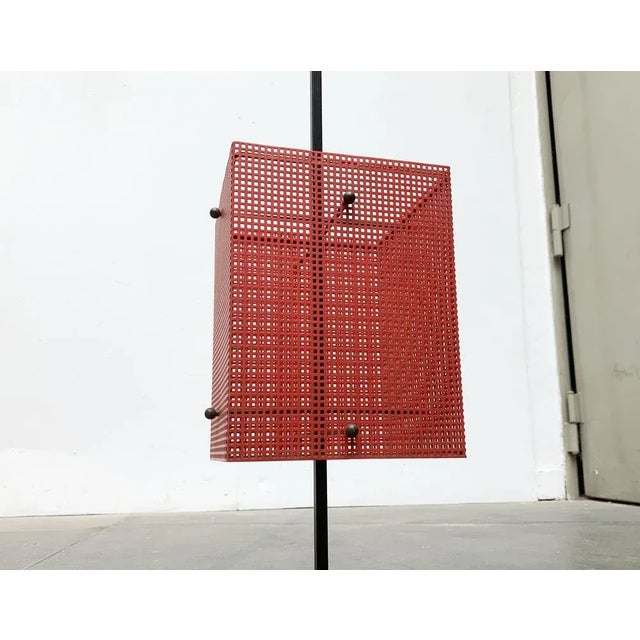 Minimalist mid century shield stand made of perforated sheet in red and black. Cubic shapes and clear lines go through...