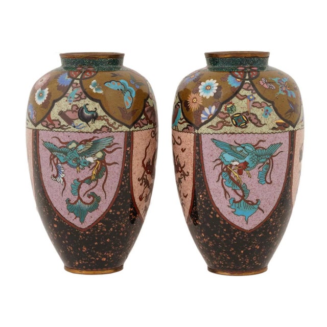 A striking pair of Japanese cloisonné enamel vases featuring bold reserves of phoenix and dragon motifs set against a...