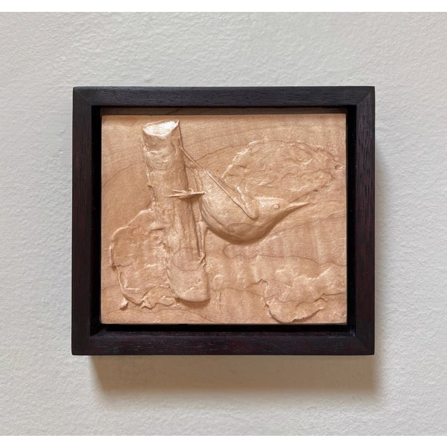 This artwork features a meticulously carved depiction of a nuthatch perched on a textured branch, showcasing the artist's...