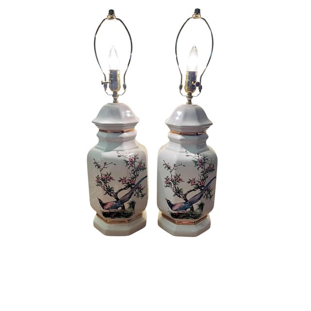 A charming pair of vintage porcelain table lamps featuring elegant transfer birds perched among flowering branches in a...