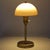 Small mid-century era table lamp or task lamp has a brushed brass finish and a lightweight, cream-yellow dome 'mushroom'...