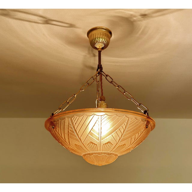 French Art Deco Pendant Light featuring a pink glass shade with geometric pattern and stylised floral ornaments mounted on...