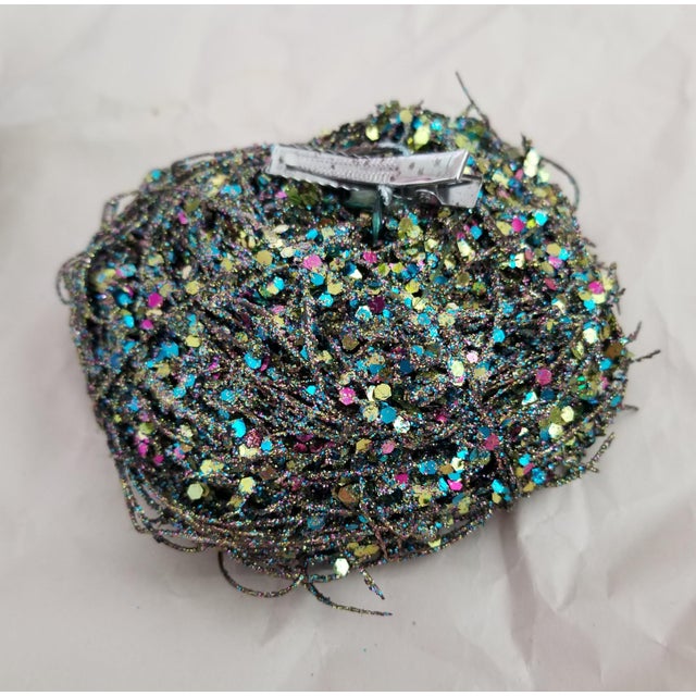 A set of four bird nests in glittery shades of aqua, blue and green, each holding two soft sheen aqua eggs. Clips on the...