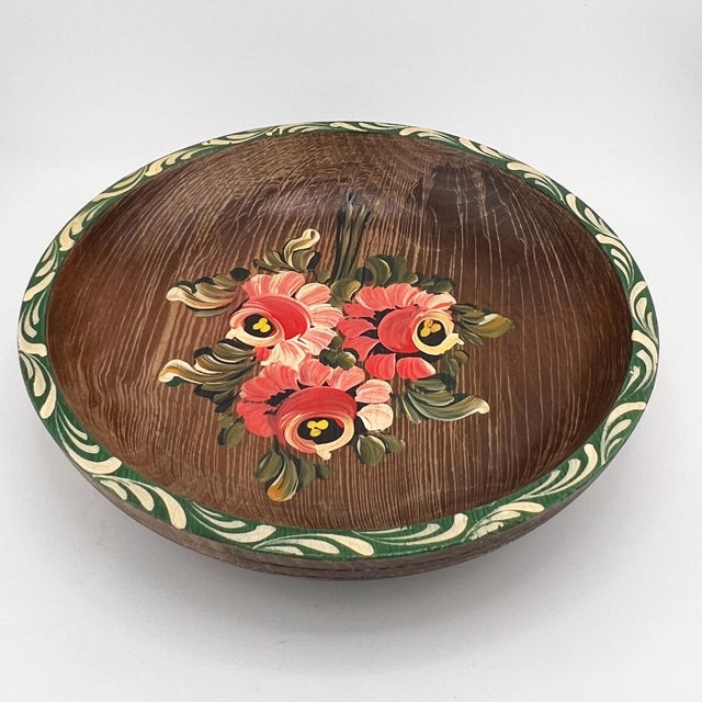 A richly patinated mid-century hand-painted wooden bowl featuring vibrant floral decoration in the European folk art...