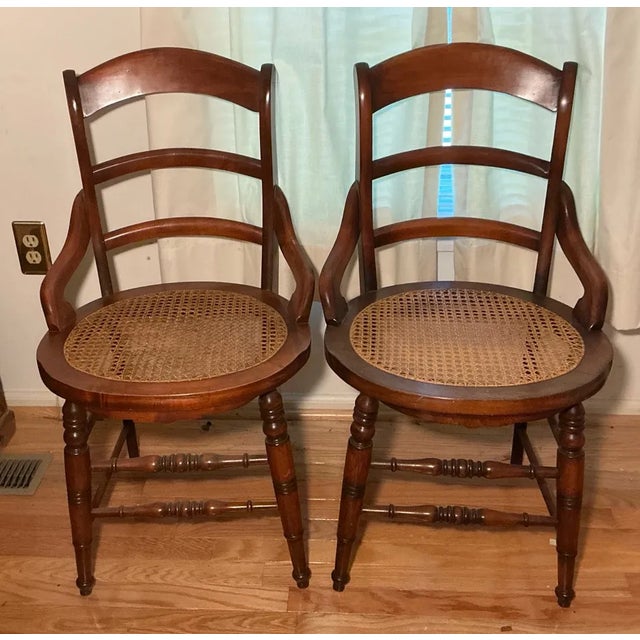 A charming pair of Victorian ladder-back arm chairs featuring round hand-caned seats — a classic form that embodies late...