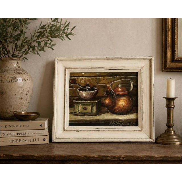 A charming signed oil still life dated 1989, depicting an old-fashioned coffee grinder alongside a glowing copper kettle....