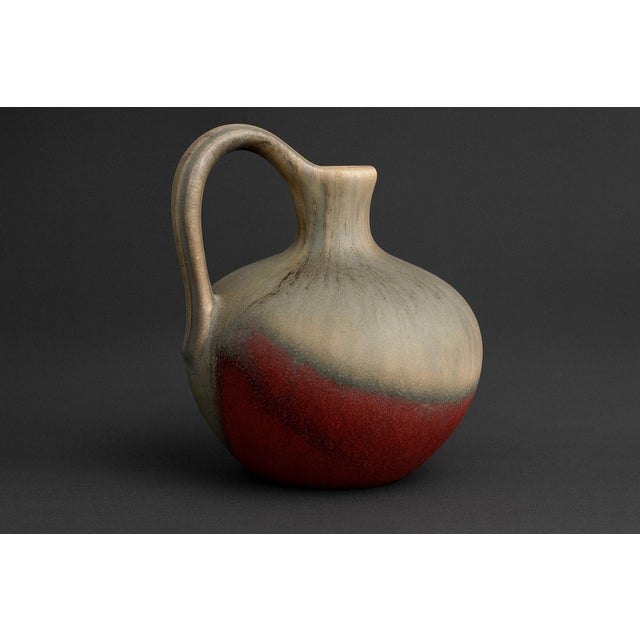 A mid-century jug vase by JOPEKO, West Germany, featuring a compact form and bold fat-lava glaze. The surface is a dynamic...