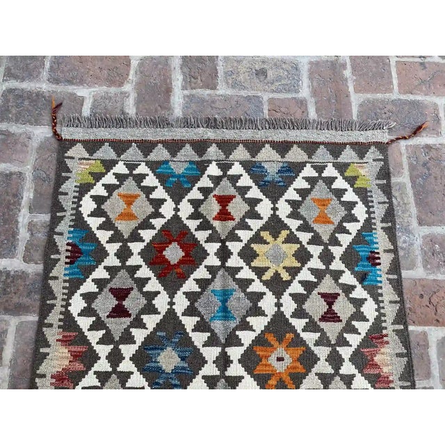 Brighten up your space with this stunning handwoven wool kilim, featuring a colorful tribal diamond design. The intricate...