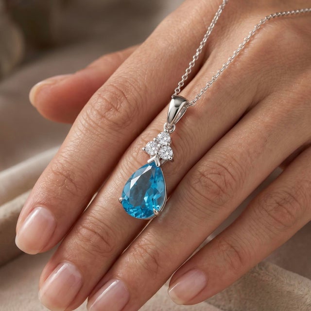 This exquisite pendant features a stunning pear-shaped blue topaz gemstone, radiating a brilliant, icy-blue hue that...