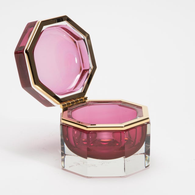 The Hand-Blown Murano Box in Ruby with Brass Fittings is a jewel-like objet d’art, designed to captivate with its opulent...
