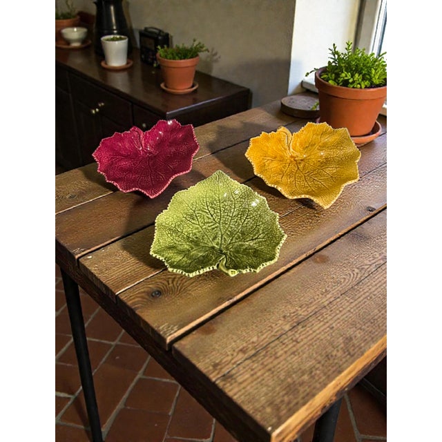 The product is a set of three colorful ceramic dishes by Bordallo Pinheiro, known for their distinctive majolica...