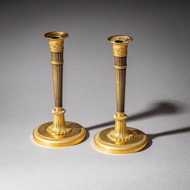A pair of elegant Empire candlesticks crafted from partially fire-gilded bronze, dating to the early 19th century. Each...