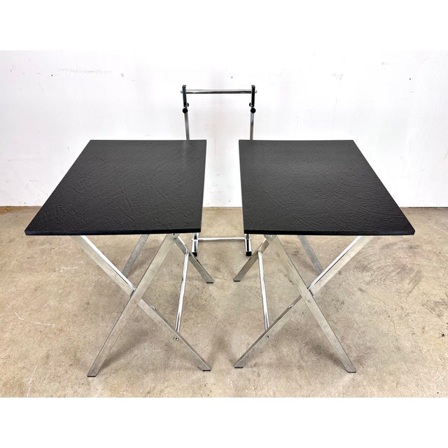 A fabulous 1970s modernist set including two folding black faux slate top tables with chrome legs together with matching...