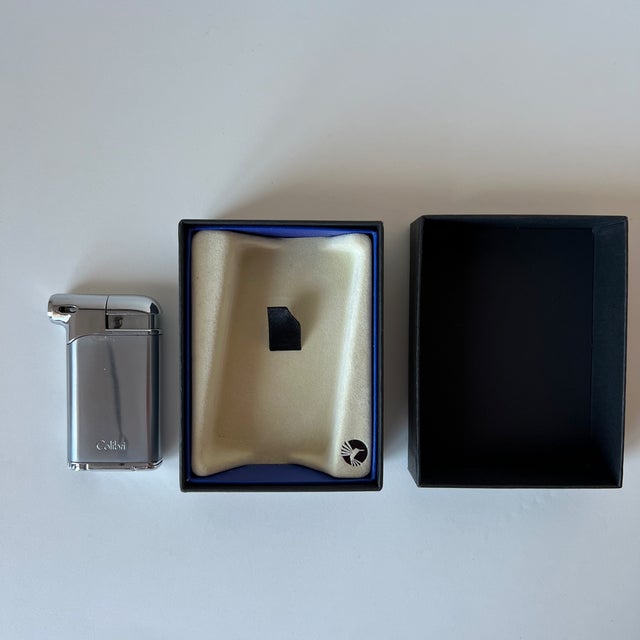 An authentic vintage butane lighter by the prestigious British manufacturer Colibri. This model features a sophisticated...