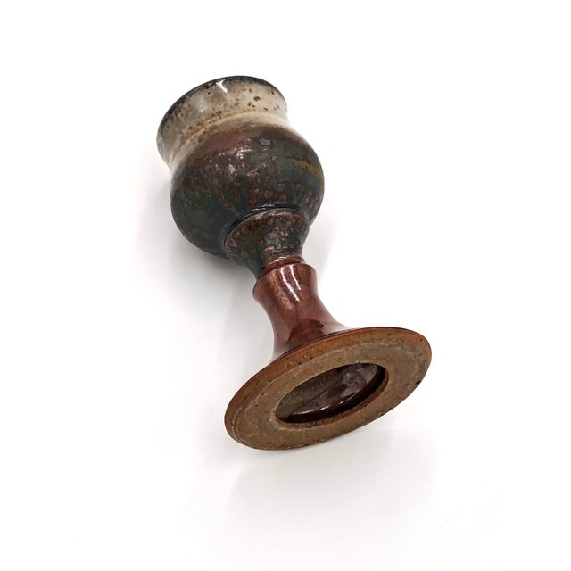 This handmade studio pottery goblet has a glazed, rust-colored base and a multi-hued/speckled bowl in shades of cream,...