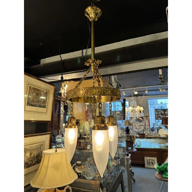 Antique Brass Three Light Tudor Revival Quatrefoil Pattern Chandelier. Unique frosted Steuben style globes as shown....