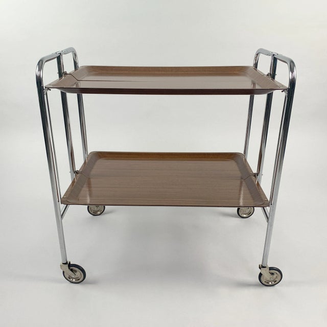 Mid-Century Modern, vintage serving tea cart consisting of laminated wood and chrome. Produced in Germany in the 1950s....