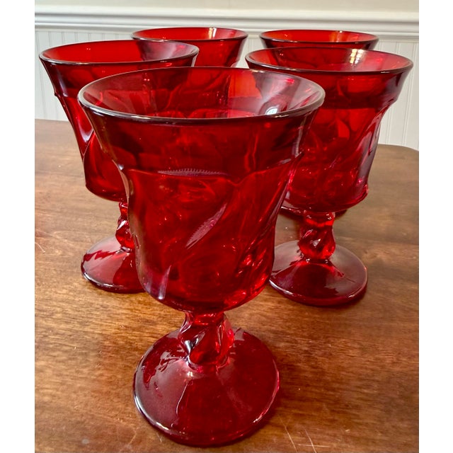 Five vintage Fostoria Jamestown Ruby Red Water Goblets, distinguished by their vibrant deep red color and elegant pressed...