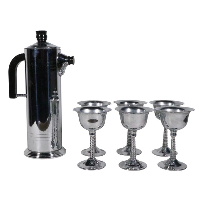 Chrome and plastic cocktail set including a shaker ( marked L.B. Chromium Plated ) and six chrome cocktail glasses. The...