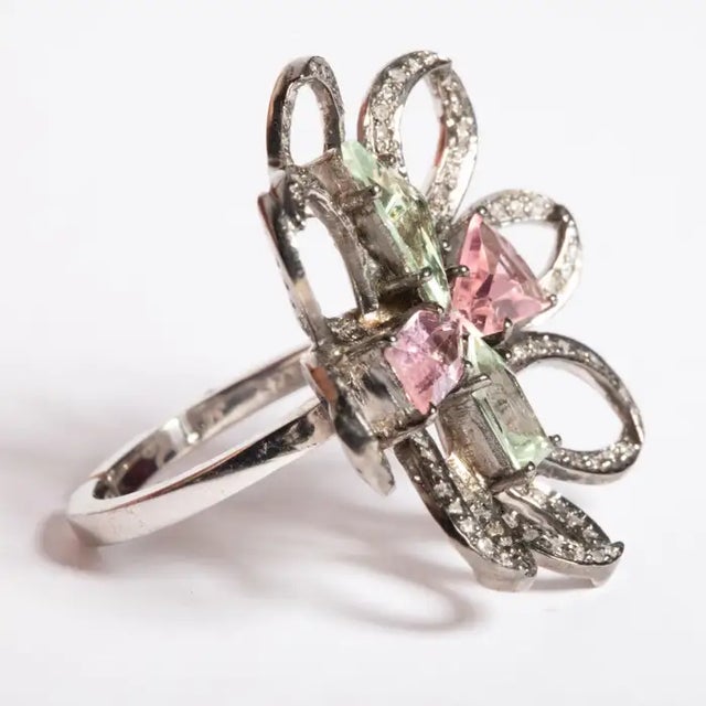 Unusually cut and faceted green aquamarine and morganite stones create the center of this flower ring. The petals are...