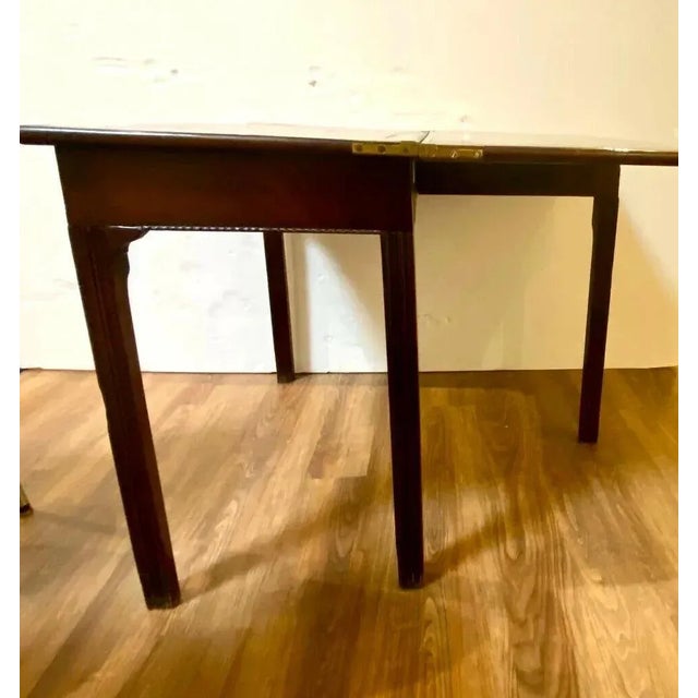 An 18th century george iii mahogany game table featuring a serpentine top opening to a finished surface, conforming frieze...