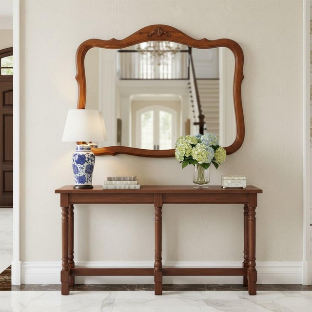 Elegant vintage French Provincial wall mirror featuring a gracefully shaped serpentine frame with carved shell crest...