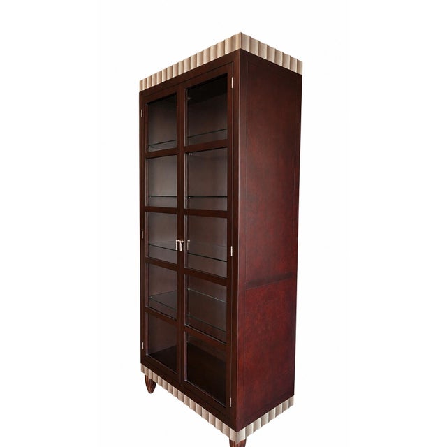 A striking contemporary display cabinet featuring rich cherry-finished wood, glass-paneled doors, four glass display...