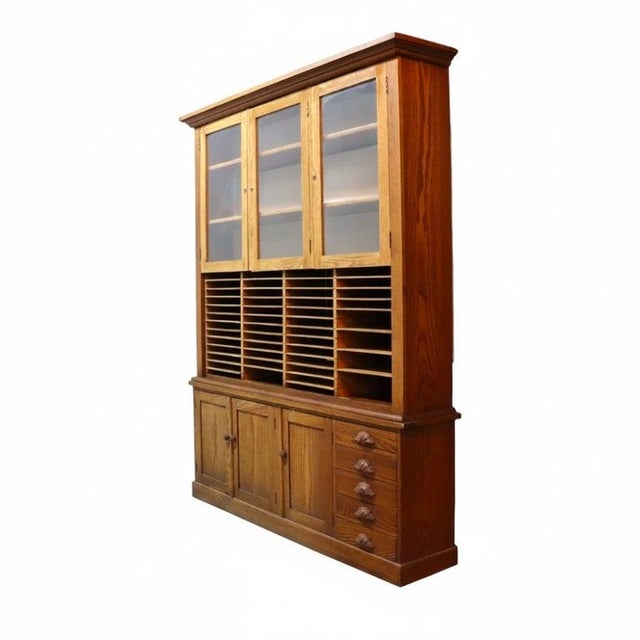 An impressive antique oversized two-piece country store cabinet, crafted from solid oak around 1910. This substantial...