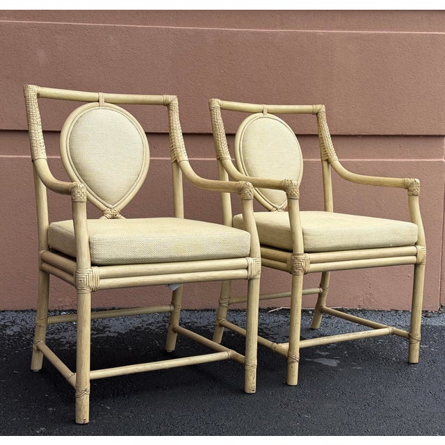 Elegant pair of rattan dining armchairs by Ficks Reed, featuring distinctive teardrop-shaped upholstered backs, gracefully...