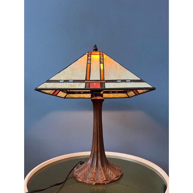 Big Tiffany table lamp with colourful stained glass shade. The base is made out of metal and the shade is made from...