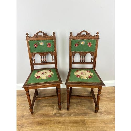 A decorative pair of Antique French chairs in Oak, featuring carved crest details, turned spindle elements and green...