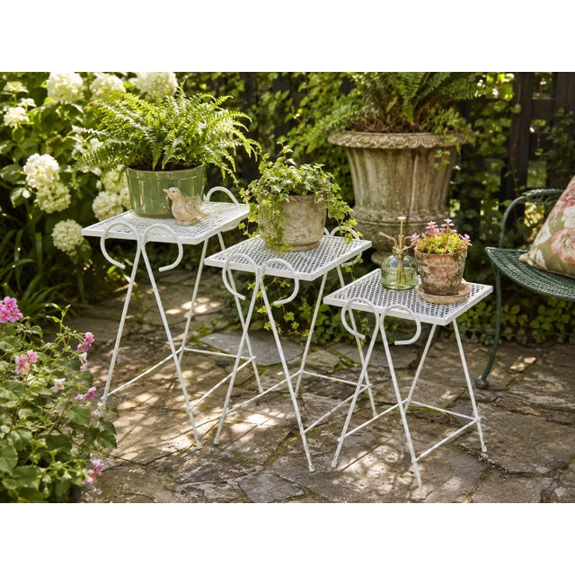 A delightful set of three vintage graduated metal nesting tables featuring white painted finishes, open diamond-mesh tops...