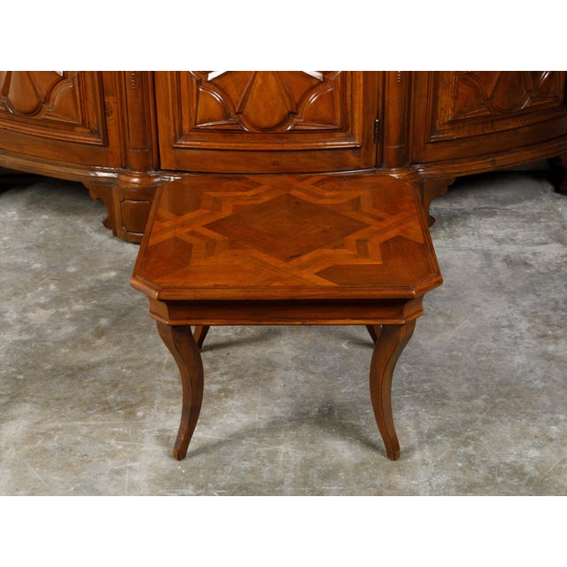 A walnut coffee table from the mid 20th century, with geometric star-inlaid top and curving legs. Created during the...