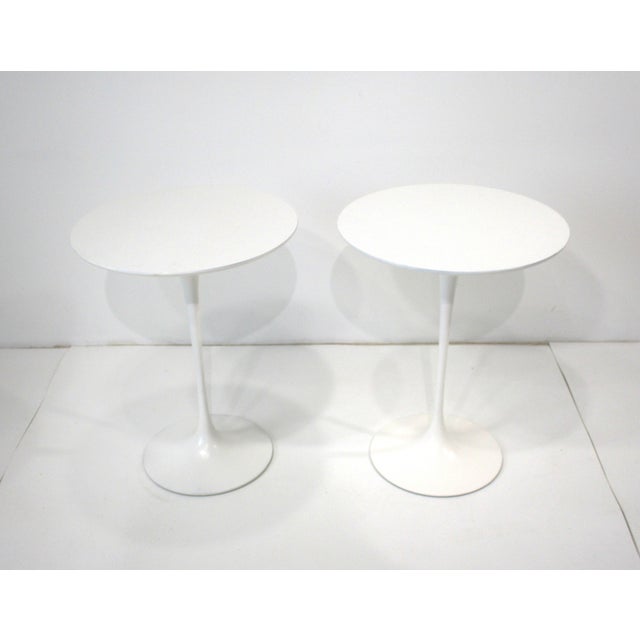 A pair of early white tulip side tables with heavy cast steel bases and laminate tops designed by artist , architect and...