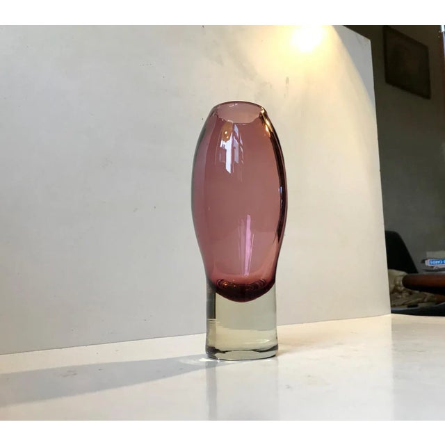 Plum colored vase in clear glass designed by Aimo Okkolin in 1970. Manufactured by Riihimaen Lasi in Finland. This vase is...