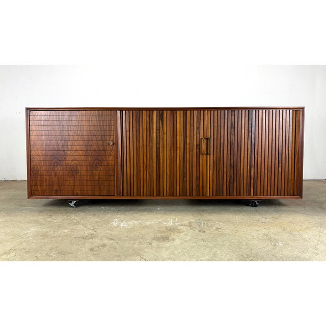 A fabulous and functional multi-purpose mid century credenza with tambour doors, a lighted pull-out bar, and space for...