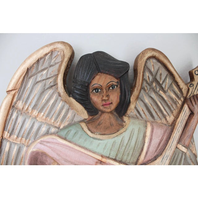 A rare trio of hand-carved wooden angels, each uniquely painted and holding a musical instrument: a harp, violin, and...