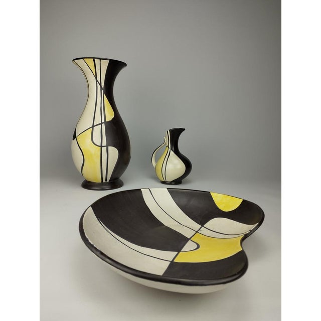 The parts of the set, consisting of a large vase, a small jug vase and a bowl, were made in 1957 by the Bay Keramik...